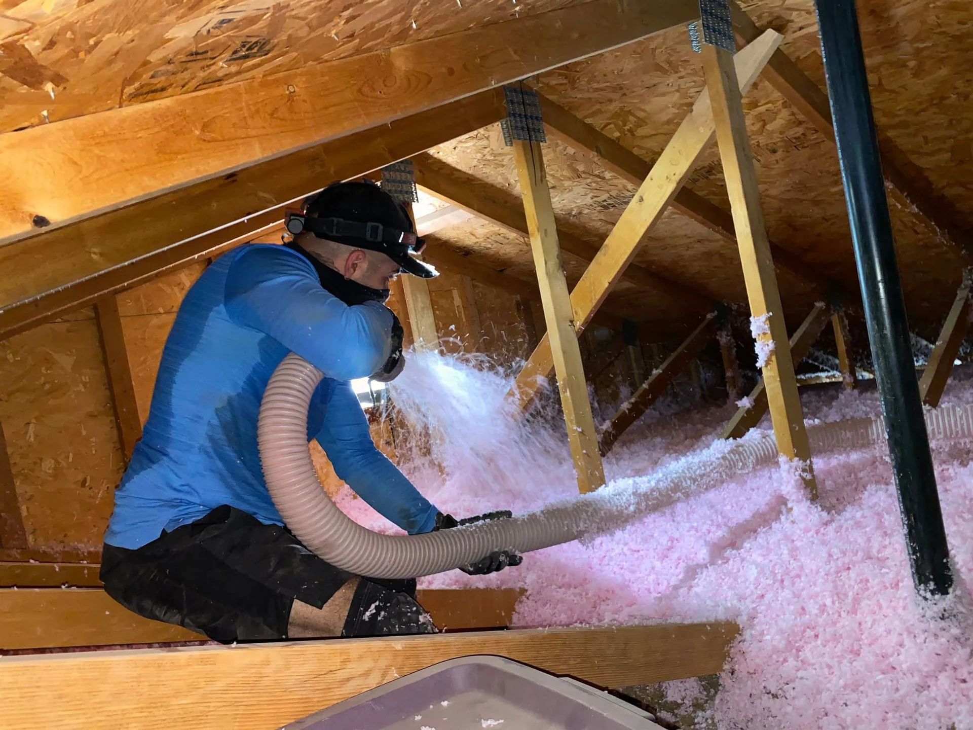 A Green Faith Solutions specialist installing blown-in attic insulation in a customer’s home